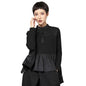 Woman wearing a black outfit with a layered design and contrasting textures against a neutral background